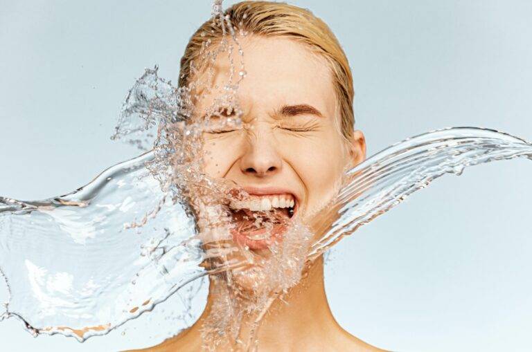 Photo of  screaming woman with drops of water around her face. Young woman with clean skin and splash of water.  Spa treatment. Girl washing her body with water. Water and body. Skin and body care